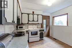 Kitchen featuring overhead and base cabinetry, double basin stainless steel sink, and white appliances -