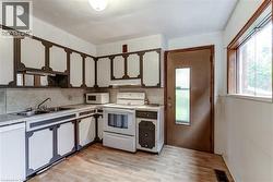 Kitchen featuring extensive cabinetry, laminate countertops, a double basin sink, and wood-finish flooring -