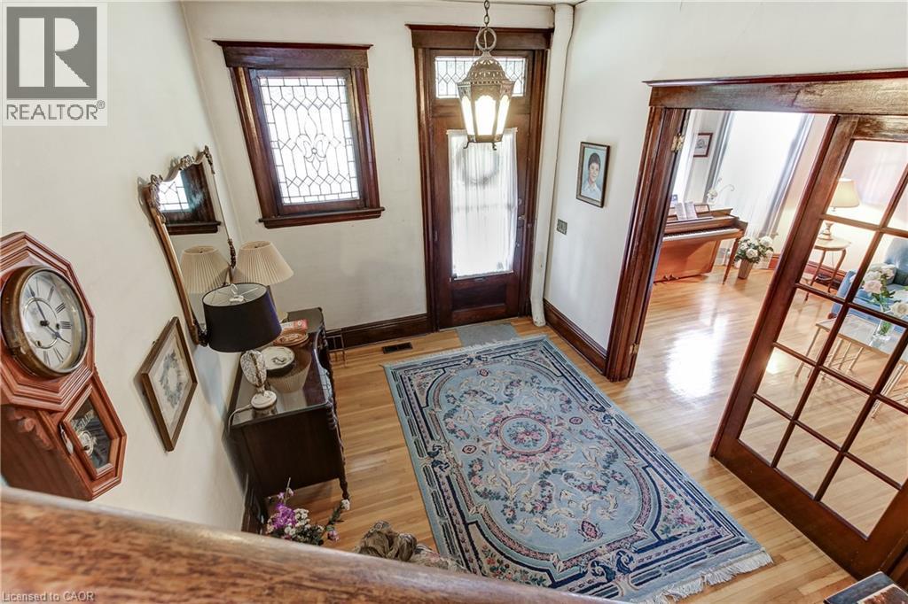Foyer featuring hardwood flooring, an ornate front door with glass paneling, a leaded glass window, and a decorative overhead light fixture - 18 Fairleigh Crescent, Hamilton, ON - Indoor Photo Showing Other Room