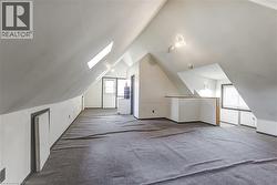 Spacious attic conversion featuring sloped ceilings, two skylights, track lighting, and gray carpeting -
