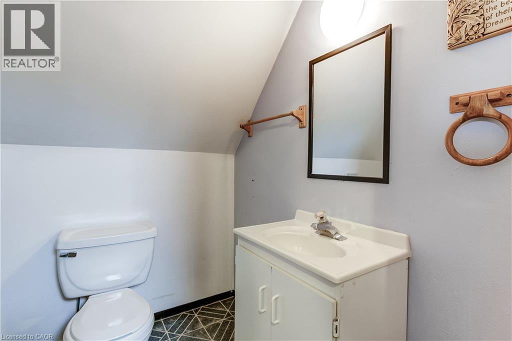 Bathroom featuring a white toilet, single vanity with integrated sink, rectangular framed mirror, and geometric patterned flooring - 18 Fairleigh Crescent, Hamilton, ON - Indoor Photo Showing Bathroom