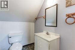 Bathroom featuring a white toilet, single vanity with integrated sink, rectangular framed mirror, and geometric patterned flooring -