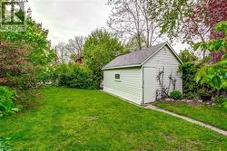 Expansive green lawn with a white wood-sided shed featuring a single door and small window -