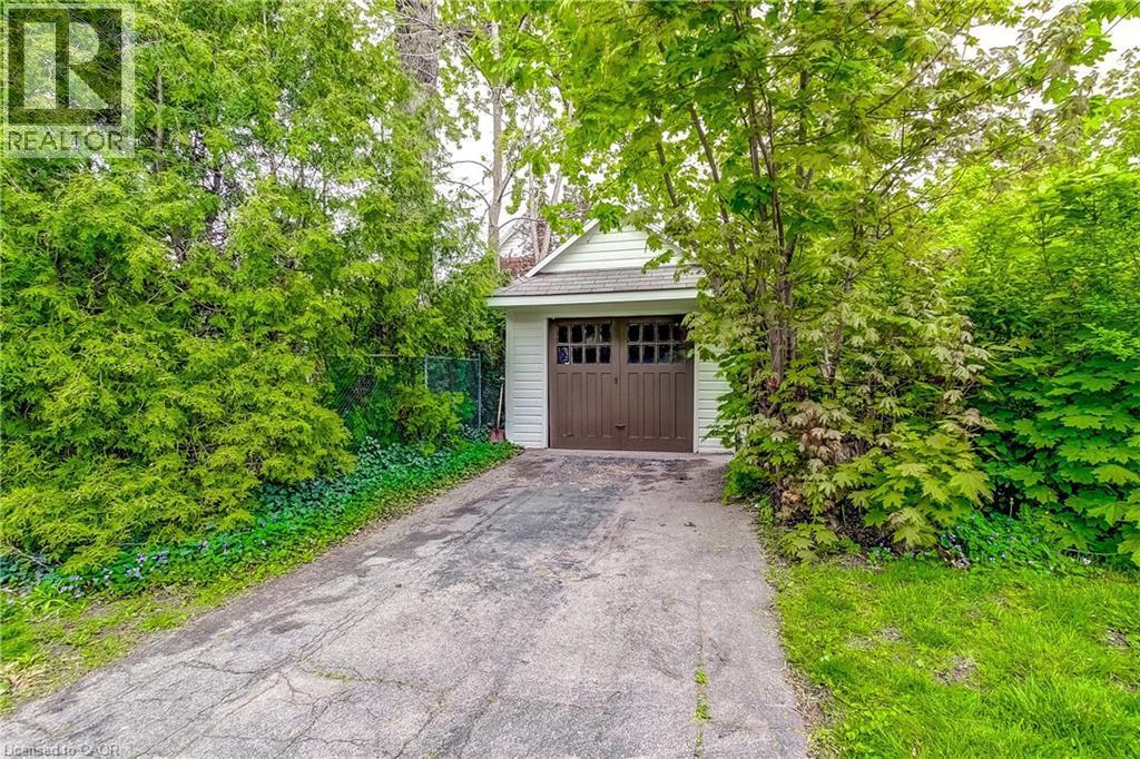 Detached single-car garage featuring light-colored siding and a brown garage door with window inserts - 18 Fairleigh Crescent, Hamilton, ON - Outdoor