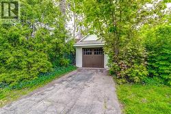 Detached single-car garage featuring light-colored siding and a brown garage door with window inserts -