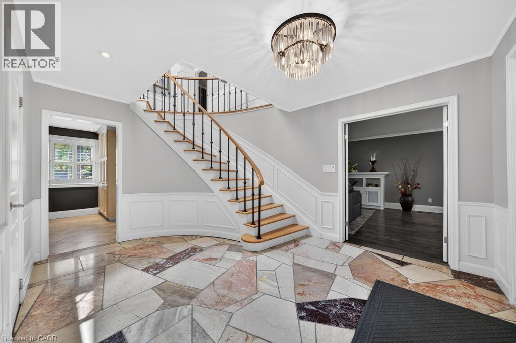 Grand foyer featuring a curved staircase with natural wood treads and iron balusters - 25 Braemar Place, Hamilton, ON - Indoor Photo Showing Other Room