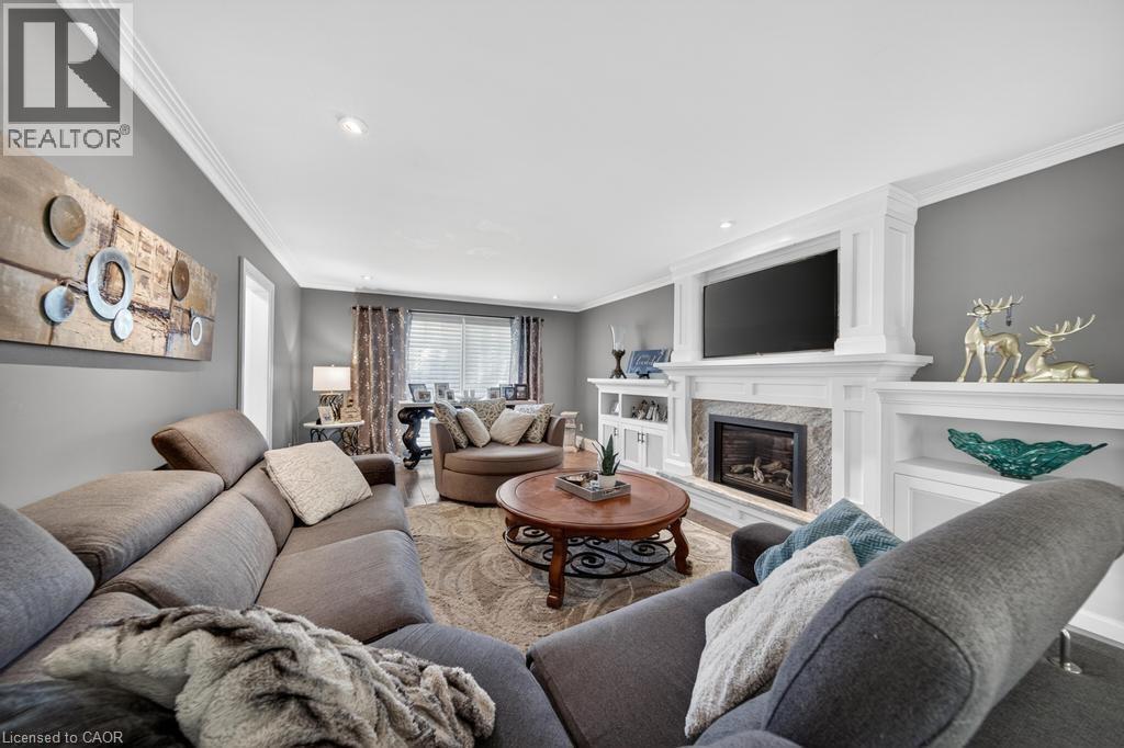 Living area featuring a gas fireplace with a stone surround, white mantel, and built-in shelving - 25 Braemar Place, Hamilton, ON - Indoor Photo Showing Living Room With Fireplace