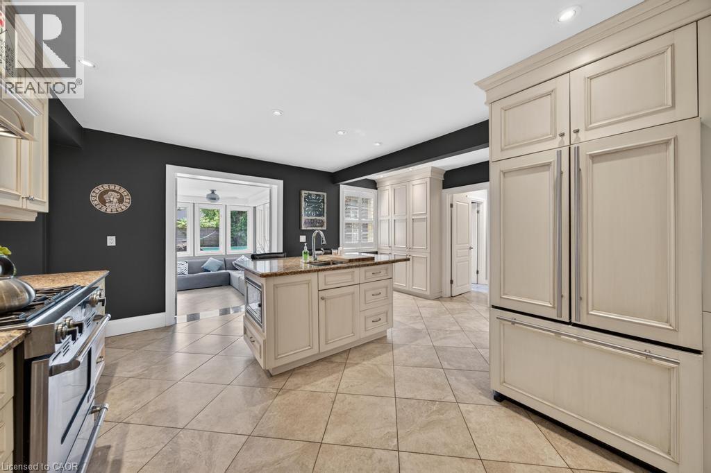 Kitchen featuring an integrated paneled refrigerator, a central island with an undermount sink and built-in microwave, stainless steel range, and tile flooring - 25 Braemar Place, Hamilton, ON - Indoor Photo Showing Kitchen