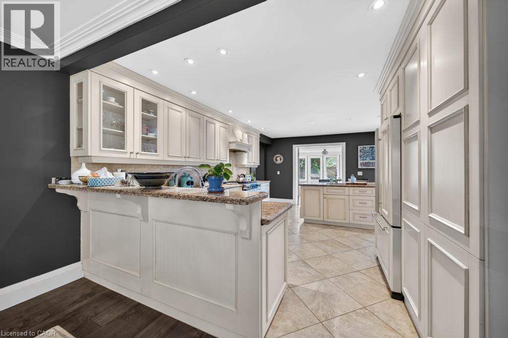 Kitchen featuring light-toned cabinetry with glass-front accents, granite countertops, recessed lighting, and a built-in paneled refrigerator - 25 Braemar Place, Hamilton, ON - Indoor