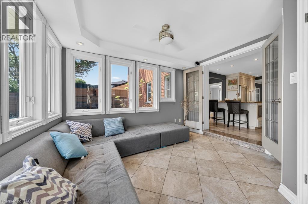Sunroom featuring a bank of windows, tiled flooring, recessed lighting, and French doors opening to a kitchen space with an island - 25 Braemar Place, Hamilton, ON - Indoor
