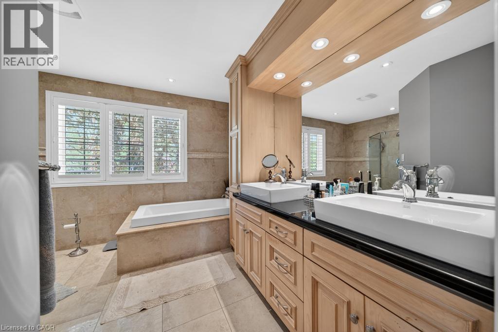 Bathroom featuring a dual vanity with vessel sinks, black countertops, and natural wood cabinetry - 25 Braemar Place, Hamilton, ON - Indoor Photo Showing Bathroom