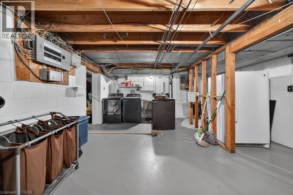 Utility area featuring a painted concrete floor, exposed wood ceiling joists, and block walls - 25 Braemar Place, Hamilton, ON - Indoor Photo Showing Basement
