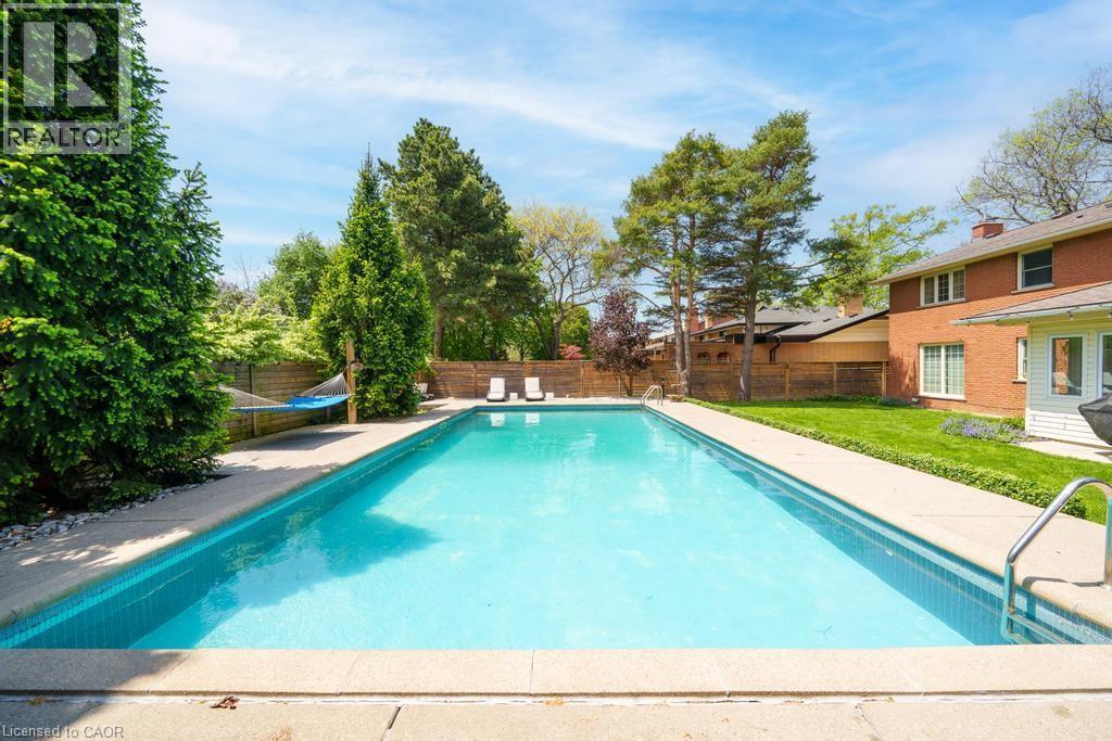Rectangular inground swimming pool with a surrounding concrete deck - 25 Braemar Place, Hamilton, ON - Outdoor With In Ground Pool With Backyard