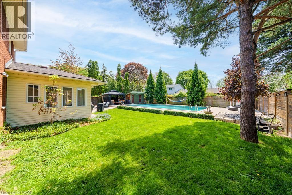 Expansive backyard with a manicured lawn, inground swimming pool, and mature trees - 25 Braemar Place, Hamilton, ON - Outdoor With In Ground Pool