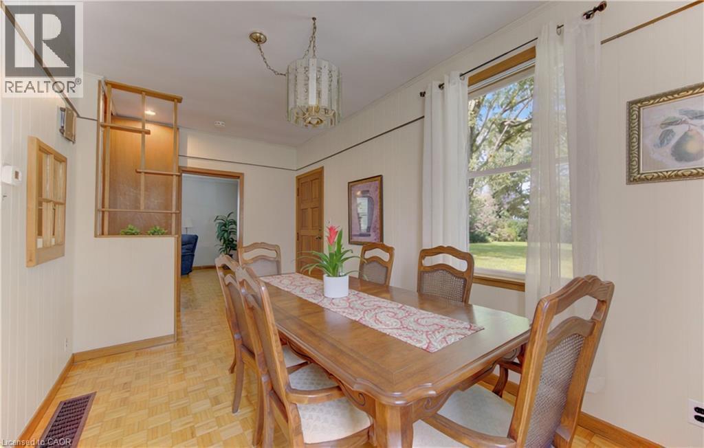 Dining area featuring wood-finish parquet flooring, a large window with natural light, and a decorative wood room divider - 1463 Kossuth Road, Cambridge, ON - Indoor Photo Showing Dining Room