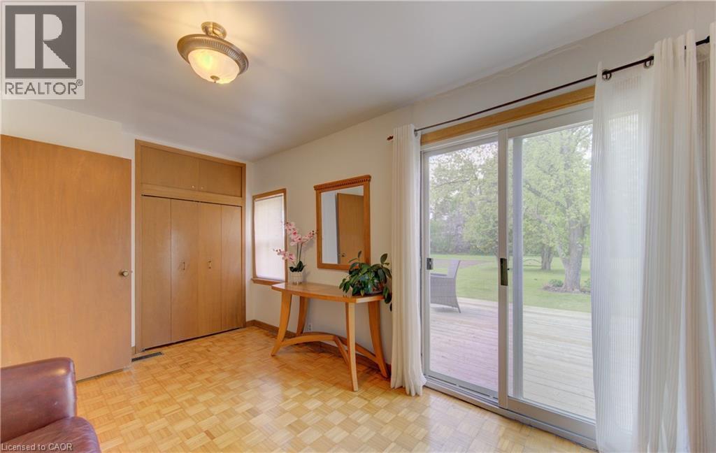 Parquet wood-finish flooring featuring sliding glass doors opening to an outdoor deck - 1463 Kossuth Road, Cambridge, ON - Indoor Photo Showing Other Room
