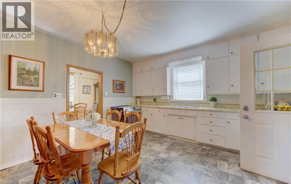 Kitchen with white upper and lower cabinetry, a window with blinds, a built-in sink, and patterned flooring - 1463 Kossuth Road, Cambridge, ON - Indoor Photo Showing Dining Room