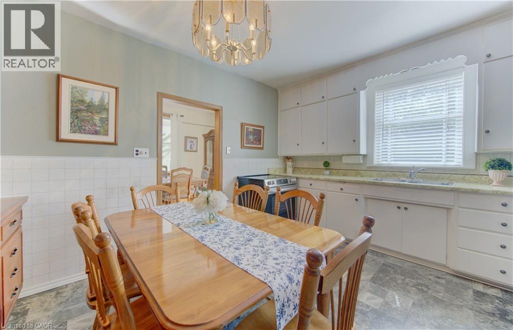 Dining area featuring wood-finish flooring, a decorative chandelier, white cabinetry, a double basin sink, and a light-colored countertop - 1463 Kossuth Road, Cambridge, ON - Indoor Photo Showing Dining Room