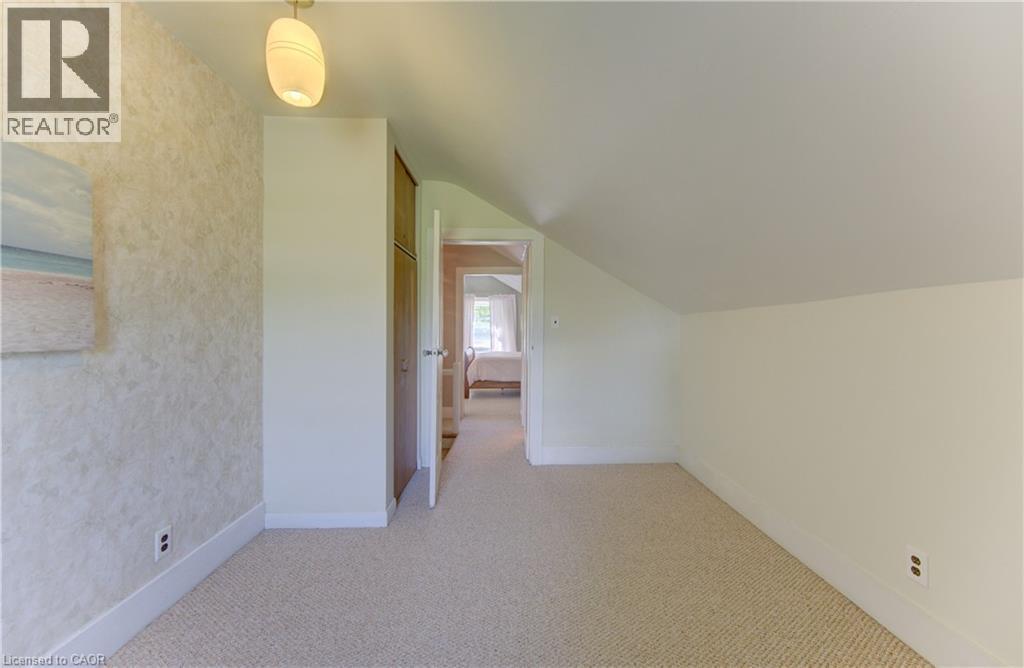 Carpeted room featuring a sloped ceiling, built-in cabinetry with wood-finish doors, and a decorative wall finish - 1463 Kossuth Road, Cambridge, ON - Indoor Photo Showing Other Room