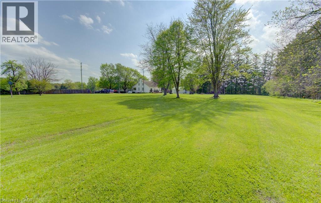 Expansive green lawn with mature trees and a residential structure in the background - 1463 Kossuth Road, Cambridge, ON - Outdoor