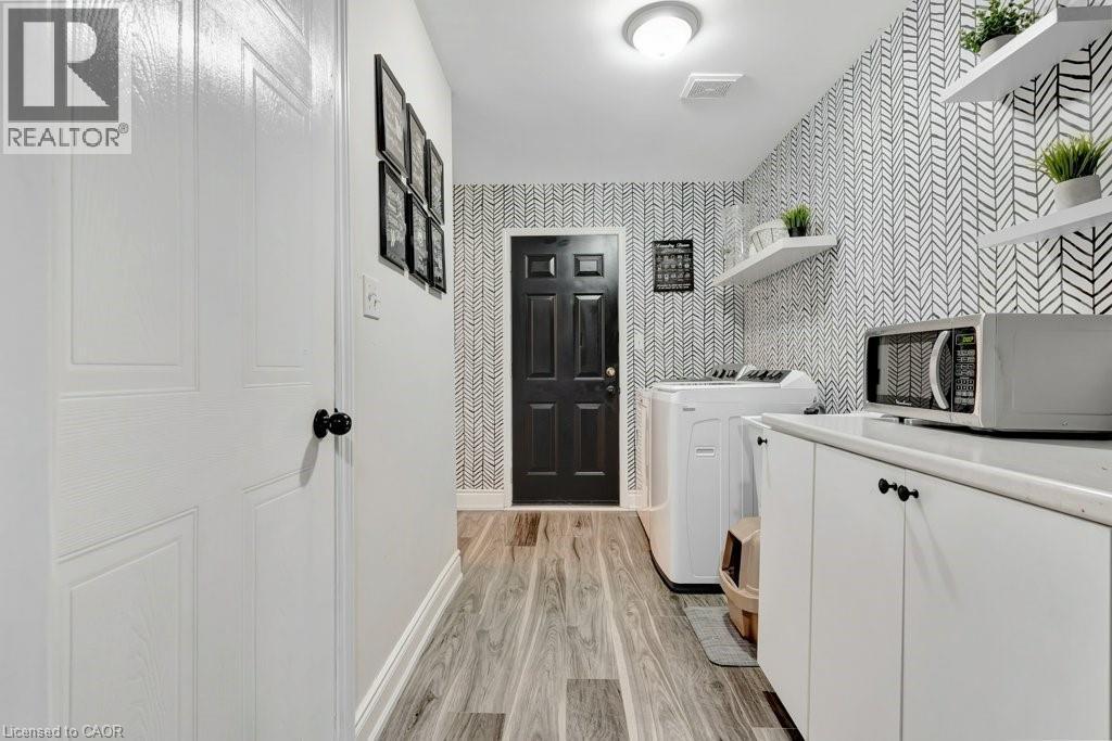 Hallway featuring wood-finish flooring and a contrasting black door - 49 Small Court, Cambridge, ON - Indoor