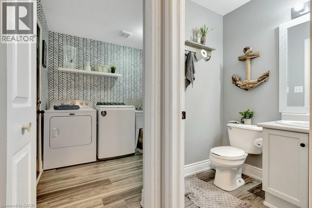 Functional laundry area featuring graphic wallpaper, a white floating shelf, and wood-finish flooring - 49 Small Court, Cambridge, ON - Indoor Photo Showing Laundry Room