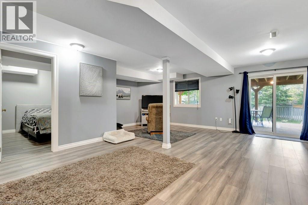 Spacious lower-level living area featuring wood-finish flooring and light gray walls - 49 Small Court, Cambridge, ON - Indoor