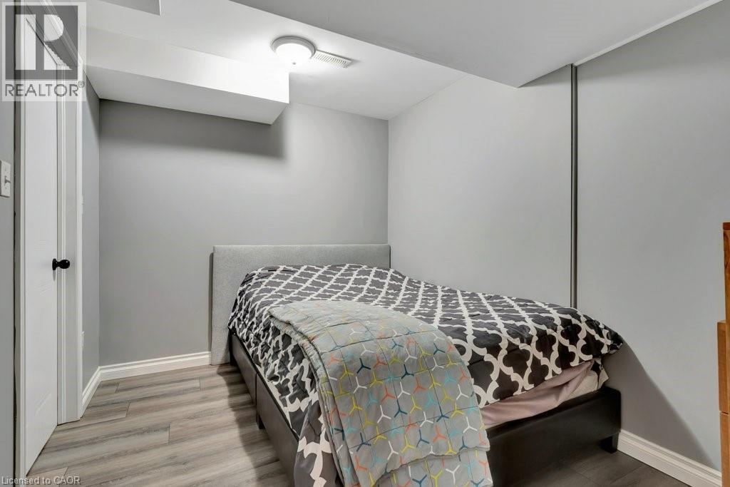 Bedroom featuring light gray walls, wood-finish flooring, white trim, and a contemporary ceiling light fixture - 49 Small Court, Cambridge, ON - Indoor Photo Showing Bedroom