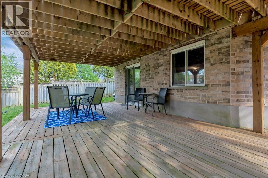 Expansive covered deck featuring natural wood decking, exposed wood joists, and a brick exterior wall - 49 Small Court, Cambridge, ON - Outdoor With Deck Patio Veranda With Exterior