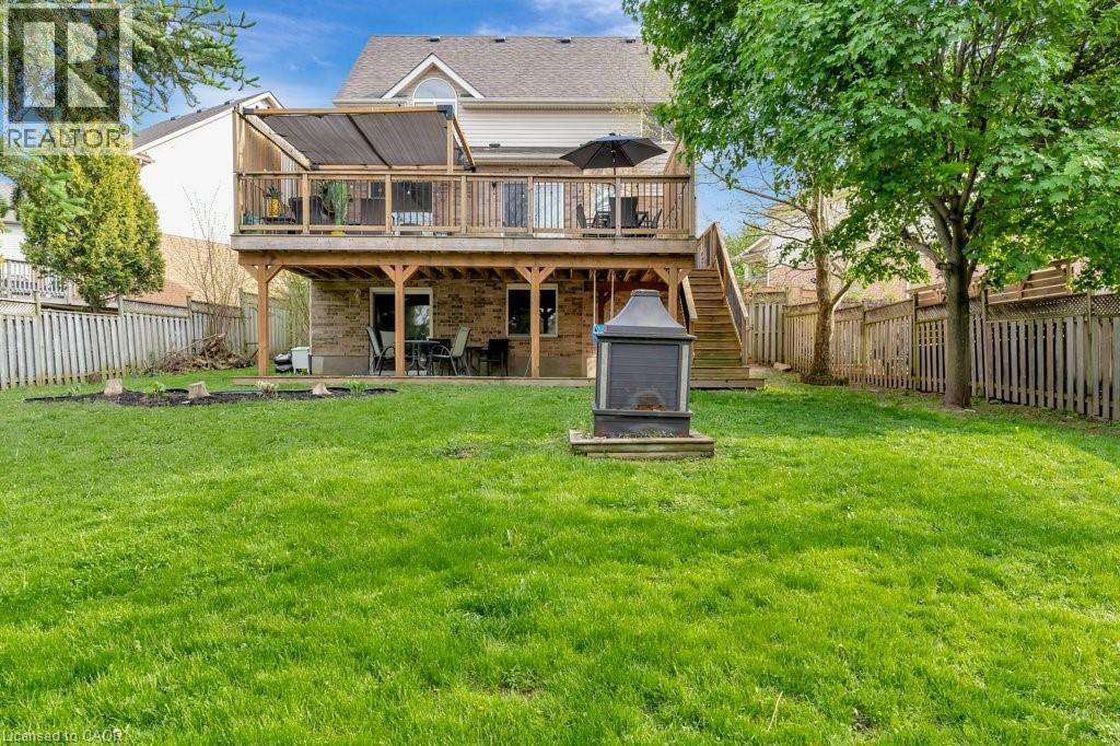 Expansive backyard featuring a manicured lawn, a two-level deck with a retractable shade canopy, and mature trees - 49 Small Court, Cambridge, ON - Outdoor With Deck Patio Veranda