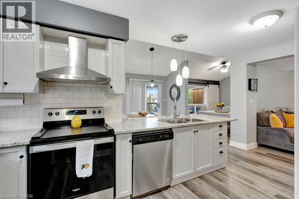 Modern kitchen featuring white shaker cabinetry, stainless steel appliances, subway tile backsplash, and light-toned countertop - 49 Small Court, Cambridge, ON - Indoor Photo Showing Kitchen With Double Sink With Upgraded Kitchen