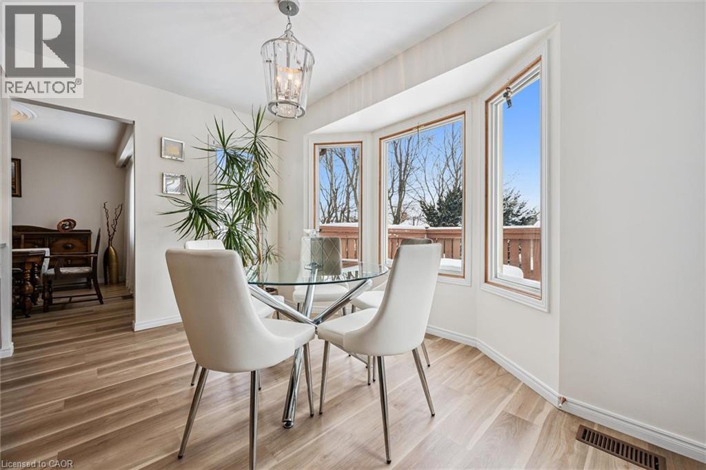 Bay window with multiple panes of glass, a contemporary ceiling light fixture, wood-finish flooring, white baseboards, and a doorway opening to an additional room - 488 Heather Hill Place, Waterloo, ON - Indoor Photo Showing Dining Room
