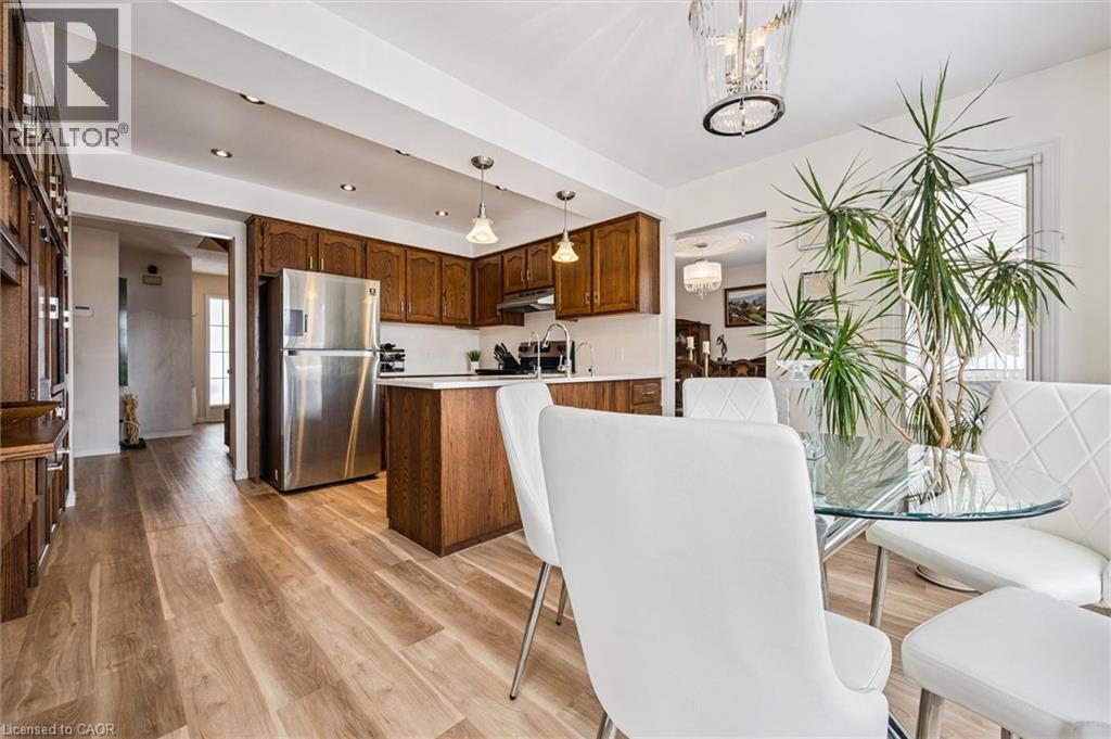 Open-concept kitchen and dining area featuring wood-finish flooring, recessed lighting, and a stainless steel refrigerator - 488 Heather Hill Place, Waterloo, ON - Indoor Photo Showing Kitchen With Stainless Steel Kitchen