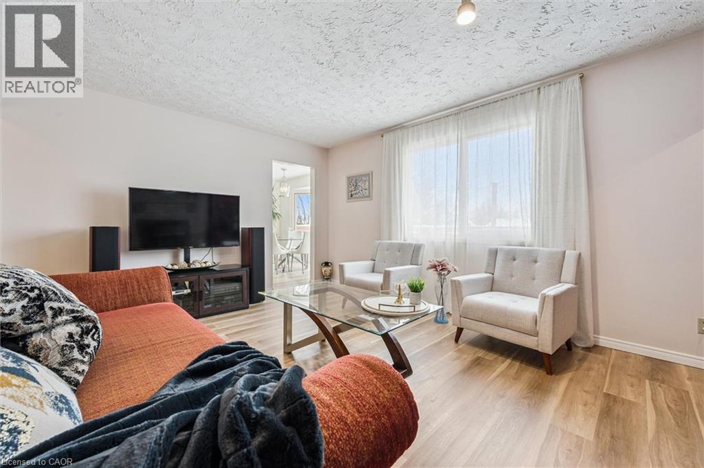 Living area featuring wood-finish flooring, a large window with sheer drapery, and a textured ceiling - 488 Heather Hill Place, Waterloo, ON - Indoor Photo Showing Living Room