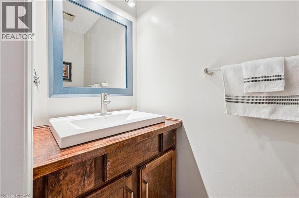 Modern rectangular vessel sink with a single-hole faucet, set on a wood-finish vanity with cabinet storage - 488 Heather Hill Place, Waterloo, ON - Indoor Photo Showing Bathroom