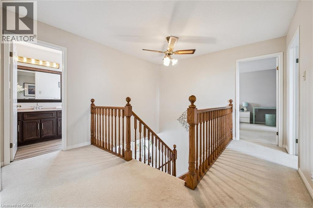 Upper-level landing featuring light-toned carpeting, a traditional wood-finish banister, and a ceiling fan with integrated lighting - 488 Heather Hill Place, Waterloo, ON - Indoor Photo Showing Other Room