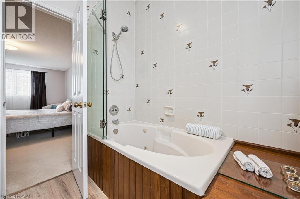 Jetted soaking tub with a glass shower enclosure and a wood-finish surround - 488 Heather Hill Place, Waterloo, ON - Indoor Photo Showing Bathroom