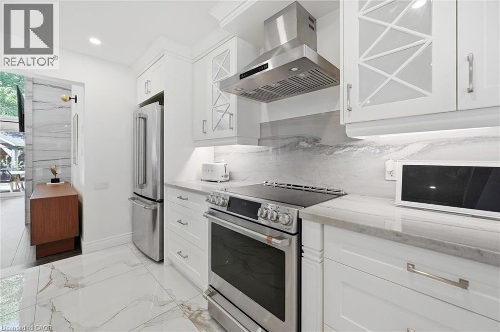 Bright kitchen featuring white cabinetry, integrated stainless steel appliances, and sleek stone countertops - 24 Glenwood Crescent, Hamilton, ON - Indoor Photo Showing Kitchen
