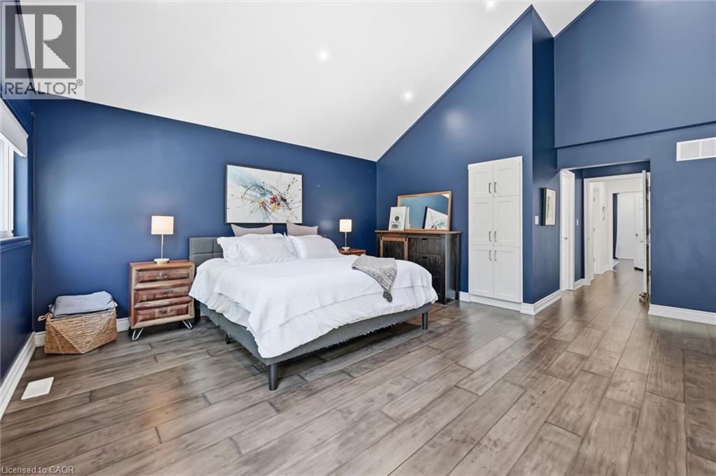 Spacious room featuring vaulted ceilings, wood-finish flooring, a built-in white storage cabinet, and a window with blinds - 24 Glenwood Crescent, Hamilton, ON - Indoor Photo Showing Bedroom
