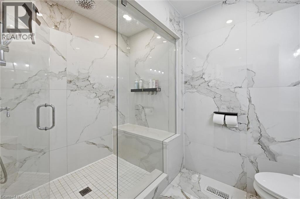 Spacious shower enclosure featuring full-height veined tile, a built-in shower bench, and a rain showerhead - 24 Glenwood Crescent, Hamilton, ON - Indoor Photo Showing Bathroom