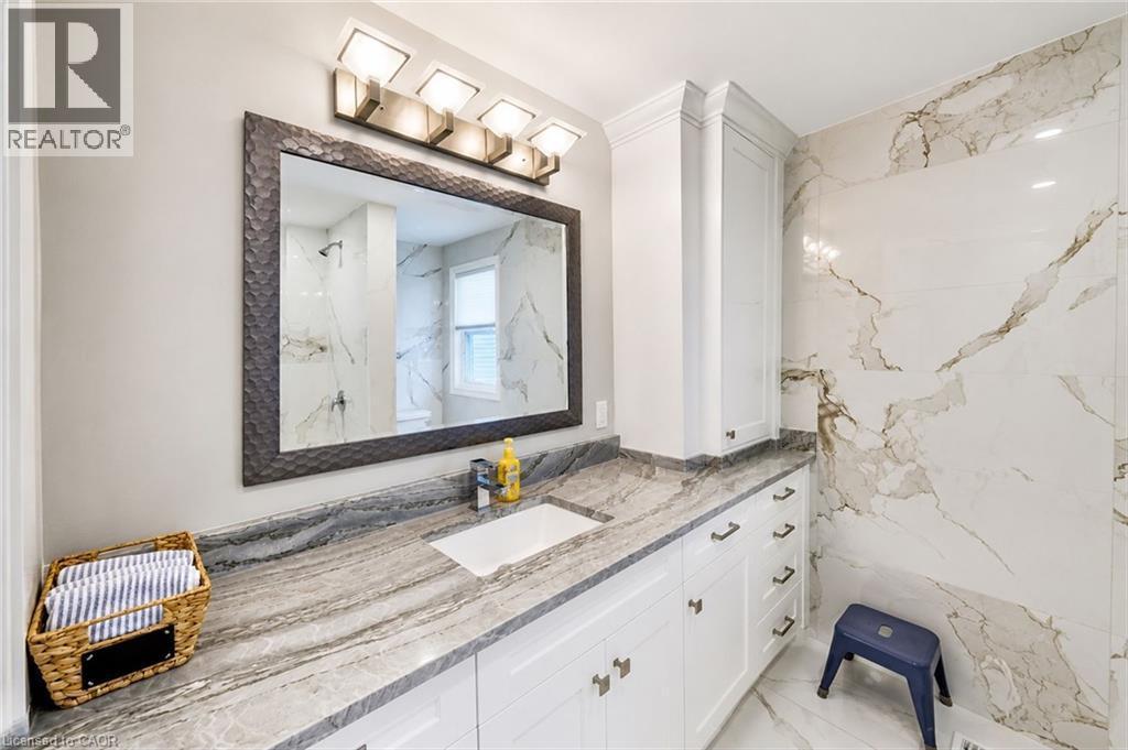 Bathroom featuring a wide vanity with a rectangular undermount sink, a patterned stone-finish countertop, and extensive white cabinetry - 24 Glenwood Crescent, Hamilton, ON - Indoor Photo Showing Bathroom