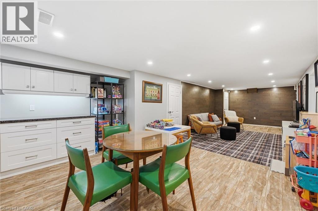 Spacious finished lower level featuring recessed lighting, wood-finish flooring, and a stone-look accent wall - 24 Glenwood Crescent, Hamilton, ON - Indoor