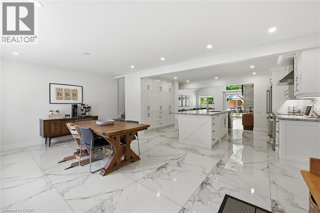 Spacious open-concept kitchen and dining area featuring large format porcelain tile flooring, white cabinetry, a substantial kitchen island with an undermount sink, recessed lighting, and stainless st - 24 Glenwood Crescent, Hamilton, ON - Indoor