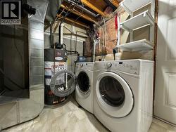 Utility area featuring a water heater, two front-load appliances, a white paneled door, and built-in shelving -