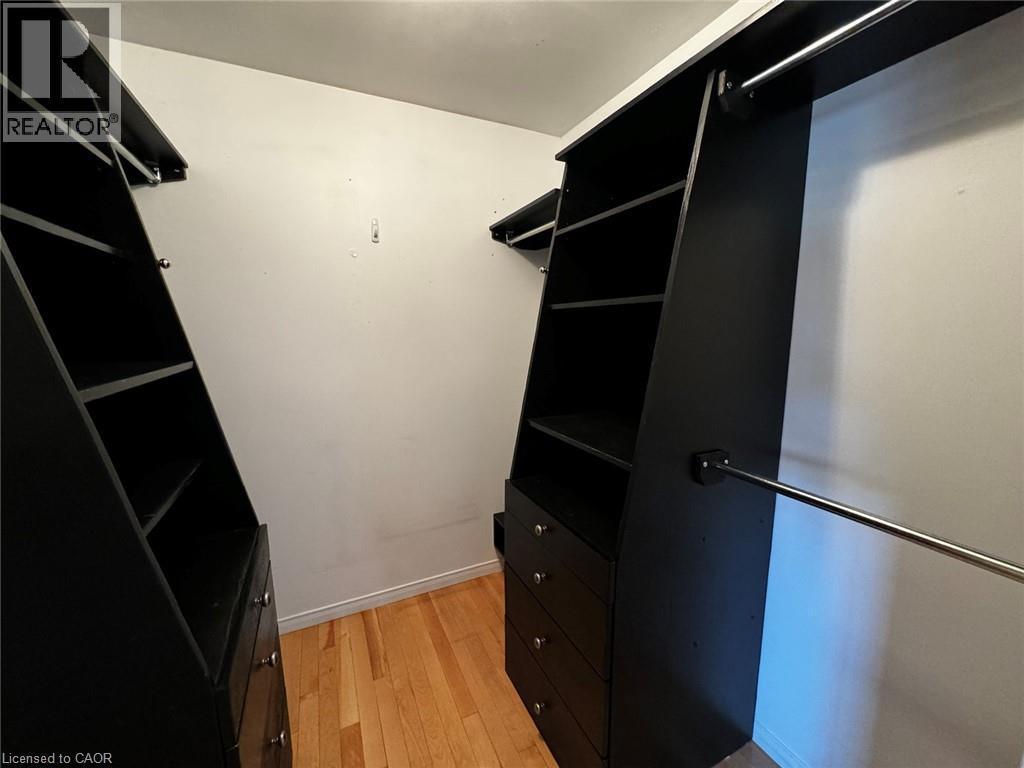 Custom closet system featuring dark cabinetry with integrated shelving, multiple drawers with silver-tone hardware, and chrome hanging rods - 37 Northcliffe Crescent, Cambridge, ON - Indoor