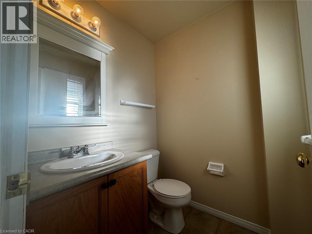 Bathroom vanity featuring a wood-finish cabinet, integrated sink, and chrome faucet - 37 Northcliffe Crescent, Cambridge, ON - Indoor Photo Showing Bathroom