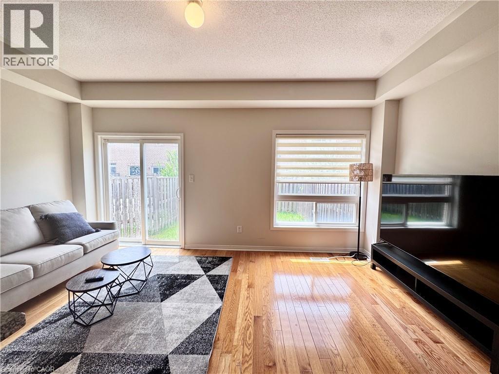 Living area featuring wood-finish flooring, a sliding glass door, and a large window with blinds - 110 Highland Road E Unit# 53, Kitchener, ON - Indoor Photo Showing Living Room