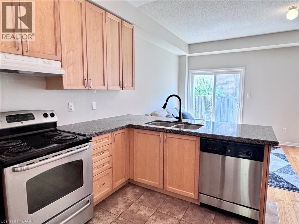 Kitchen featuring light wood cabinetry, stainless steel appliances, dark speckled countertops, and tile flooring - 110 Highland Road E Unit# 53, Kitchener, ON - Indoor Photo Showing Kitchen With Double Sink