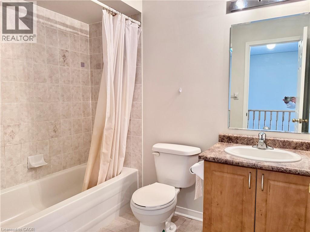 Bathroom featuring a tub and shower combination with tiled surround, a toilet, a vanity with a laminate countertop, and a mirrored medicine cabinet - 110 Highland Road E Unit# 53, Kitchener, ON - Indoor Photo Showing Bathroom
