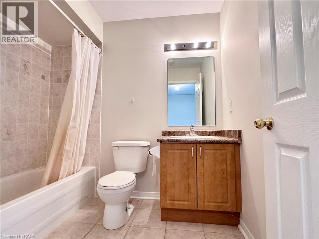 Full bathroom featuring a tub with subway tile surround, a single vanity with wood-finish cabinetry, and a countertop with integrated sink - 110 Highland Road E Unit# 53, Kitchener, ON - Indoor Photo Showing Bathroom